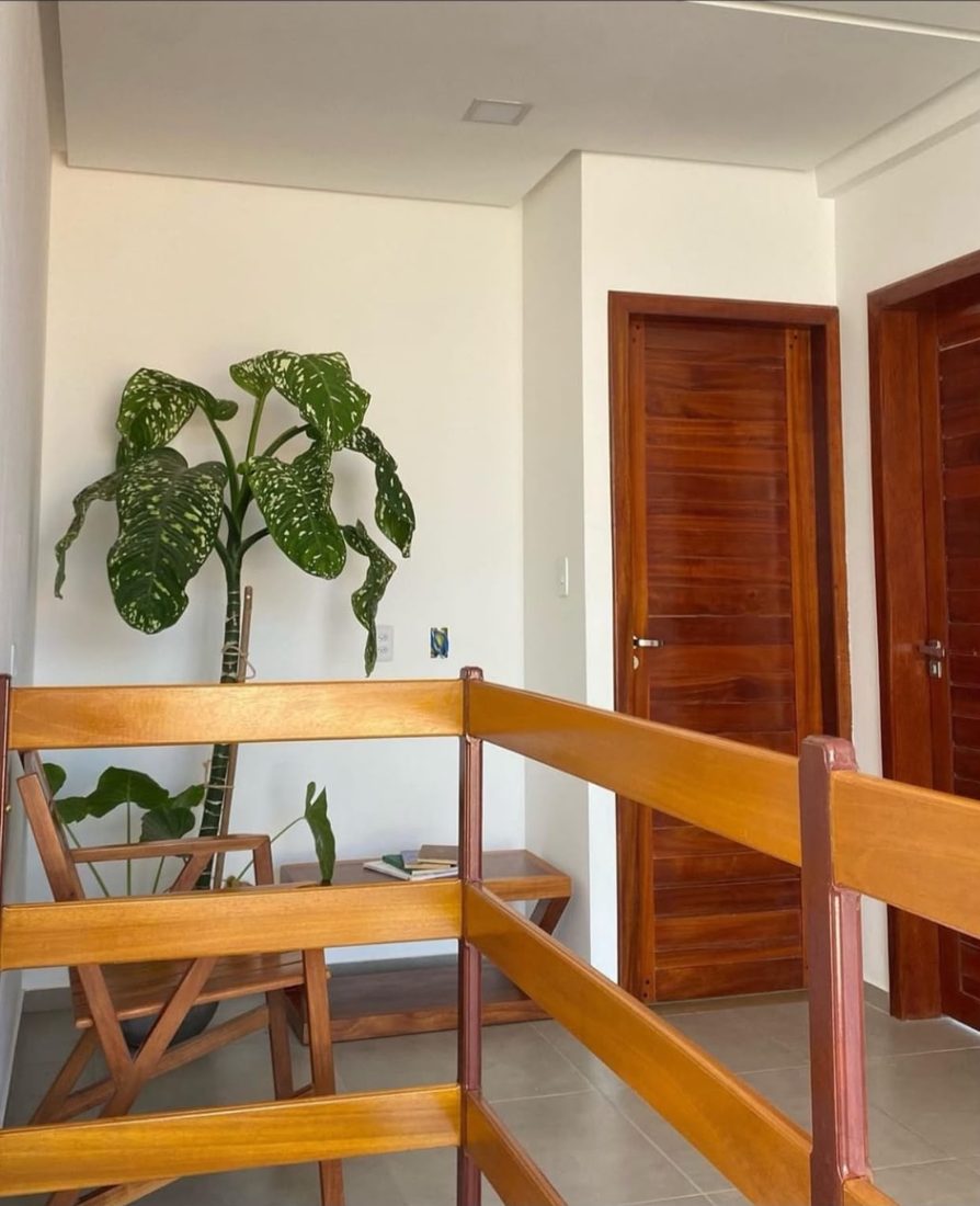 Corredor do andar superior com plantas e portas dos quartos