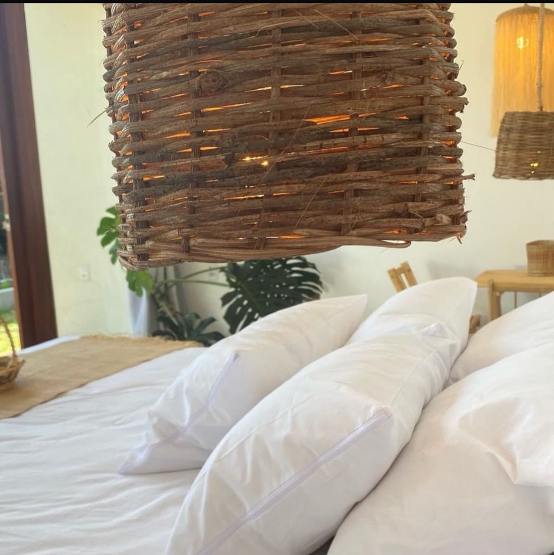Cama com travesseiros e luminária de fibra pendurada